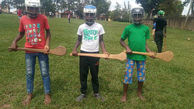 The boy in the red top has a Ugandan  made Mahogany hurley, the boy in white top a Ugandan made Mvule  hurley, and the boy in the green top an ash hurley from Ireland.