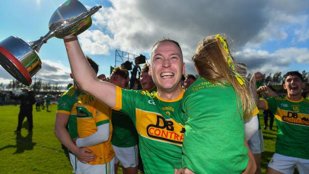 Dunloy captain Paul Shields, carrying his daughter Ada, celebrates with the cup after the Antrim County Senior Hurling Championship Final match between Dunloy Cuchullains and Loughgiel Shamrocks at Páirc Mhic Uilín in Ballycastle, Antrim. 