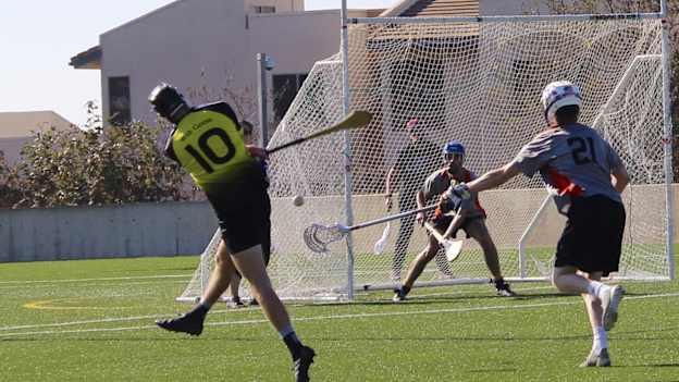 A hurler from the Wild Geese club takes a shot under pressure from a Team Eire Lacrosse player
