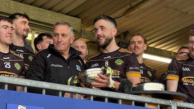 Erne Gaels captain, Ryan Lyons, receives the New York Cup from Fermanagh GAA Chairperson, John McGovern.