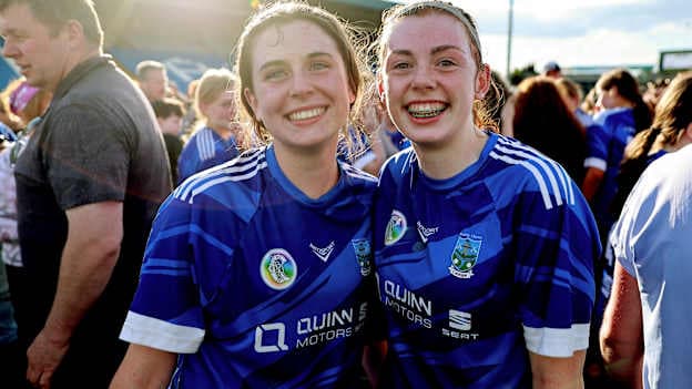 Erin's Own captain Sarah O'Gorman with her team mate Eilís Bollard celebrate after the cup final match between Erin's Own and Barryroe during the 2026 John West Féile na nGael Camogie and Hurling National Finals at Laois Hire O’Moore Park & LOTB Centre Of Excellence in Portlaoise, Laois. Photo by Thomas Flinkow/Sportsfile.