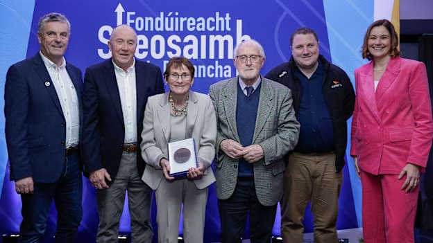 Póilín Uí Ruanaidh, Mackie Ó Ruanaidh agus Séamus McElwain ón Bhoth CLG i gcontae Mhuineacháin ag glacadh le bonn cré-rumha de chuid Fhondúireacht Sheosaimh Mhic Dhonncha ó Lorcán Mac Gabhann, Ceannasaí Ghlór na nGael, Ciarán Mag Uidhir, Oifigeach Gaeilge CLG Uladh agus an láithreoir spóirt Gráinne McElwain