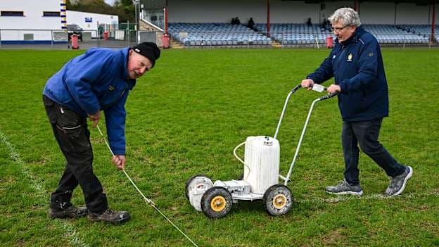 Sixmilebridge club members Fran McInerney, left, and Noel Fitzgerald, line the pitch before the 2025 AIB Munster GAA Hurling Senior Club Championship semi-final match between Éire Óg Ennis and Loughmore-Castleiney at Sixmilebridge in Clare. Photo by Ray McManus/Sportsfile.