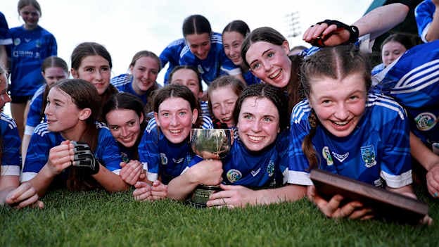 Erin's Own players celebrate with the trophy after the cup final match between Erin's Own and Barryroe during the 2026 John West Féile na nGael Camogie and Hurling National Finals at Laois Hire O’Moore Park & LOTB Centre Of Excellence in Portlaoise, Laois. Photo by Thomas Flinkow/Sportsfile.