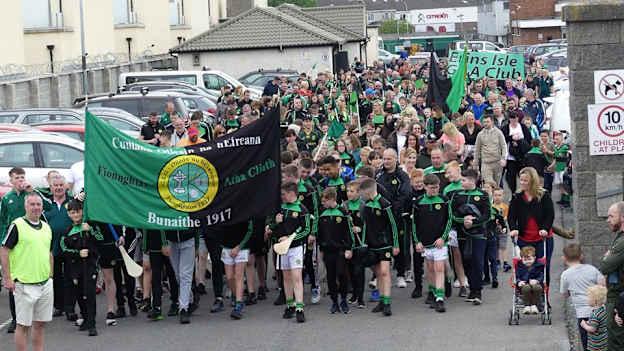 Erins Isle GAA club members march towards their club grounds after completing their 'Miles for Isles' sponsored walk.