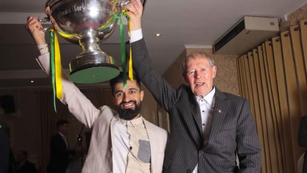 Leitrim hurler Zak Moradi holds up the Lory Meagher Cup with GAA commentator, Micheál Ó Muircheartaigh. 