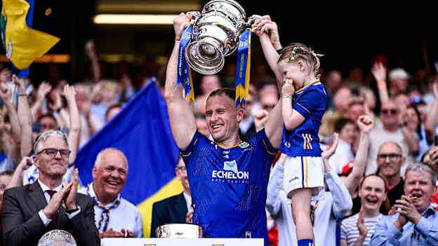 Wicklow captain Dean Healy lifts the Tailteann Cup alongside his daughter Fia after the Tailteann Cup final match between Down and Wicklow at Croke Park in Dublin. Photo by Ben McShane/Sportsfile