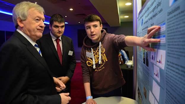 Dylan Bagnall, from The Kings Hospital, Dublin, explains his studies which he exhibited at the Young Scientist Exhibition to Ard Stiúrthóir of the GAA Páraic Duffy and Brian Carroll at the 2015 Youth Forum.