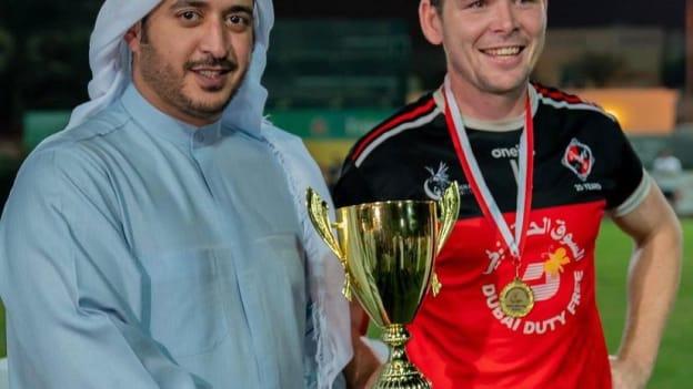 Khalid Bin Hamad, a member of the Bahrain Royal Family, presents Dubai Celts captain, Barry Canavan, with the 2021 Bahrain Games Men's Senior Cup. 