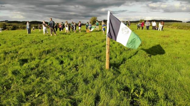 Laochra Óg volunteers plant a club flag on the 8.3 acre site where they'll develop their new home. 