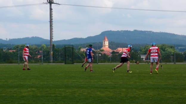 The first ever Czechia Hurling Championship match between Prague Hibernians and Píobairí Strakonice plays out before the vista of the Czech countryside. 