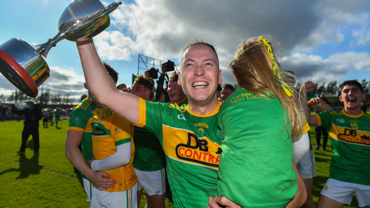 Dunloy captain Paul Shields, carrying his daughter Ada, celebrates with the cup after the Antrim County Senior Hurling Championship Final match between Dunloy Cuchullains and Loughgiel Shamrocks at Páirc Mhic Uilín in Ballycastle, Antrim.