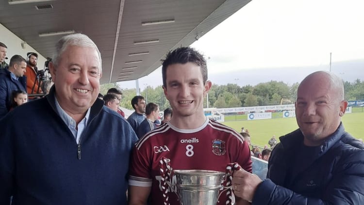 Slaughtneil captain Cormac O’Doherty with the Fr Collins Cup, alongside Kieran Leadon of Leadon Timberframe and Derry GAA Chairperson John Keenan. Photo: Derry GAA.