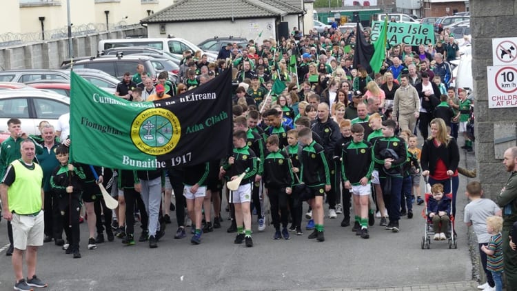 Erins Isle GAA club members march towards their club grounds after completing their 'Miles for Isles' sponsored walk.