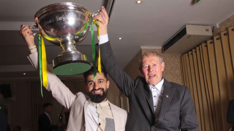 Leitrim hurler Zak Moradi holds up the Lory Meagher Cup with GAA commentator, Micheál Ó Muircheartaigh.