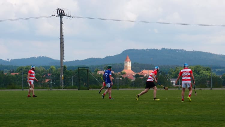 The first ever Czechia Hurling Championship match between Prague Hibernians and Píobairí Strakonice plays out before the vista of the Czech countryside.
